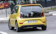 Der VW Up (2016) fährt in einer Stadt um eine Linkskurve, von hinten fotografiert.