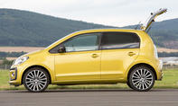 Der VW Up (2016) steht mit geöffneter Heckklappe vor einem Eifelpanorama, von links fotografiert.