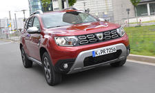 Der Dacia Duster (2018) fährt durch eine Stadt. von vorne rechts fotografiert.