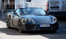 Ein Audi TT-Mule mit der Karosserie eines Porsche 718 fährt über einen Parkplatz, von vorne rechts fotografiert.