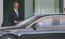 Friedrich Merz steht hinter seinem ausschnittsweise zu sehenden Kanzlerauto Mercedes S 680 Guard.