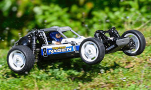 Das Bild zeigt das RC-Auto Tamiya DT-04 Fighter Nxgen fahrend von schräg vorne links fotografiert. Die Vorderräder sind in der Luft, da das Fahrzeug über eine kleine Graskuppe springt.