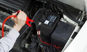 Ein Mechaniker klemmt ein Ladegerät an eine Autobatterie. 