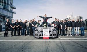 BMW M2 CS mit Nordschleifen-Rekord: Bild zeigt das gesamte Team rund um Rennfahrer Jörg Weidinger, der auf der Motorhaube des BMW M2 CS sitzt.