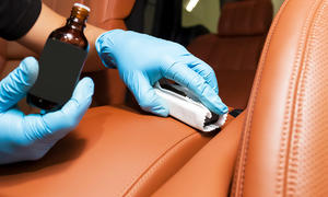 Lederkleber bei der Anwendung auf braunem Autositz