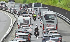 Stau auf der Autobahn, Motorradfahrer fahren zwischen den Autos durch.