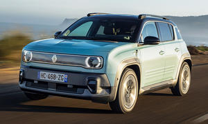 Der Renault 4 E-Tech Electric (2025) fährt eine Küstenstraße entlang, von vorne links fotografiert.