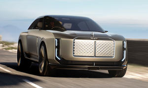 Die Studie Bentley EXP15 (2025) fährt eine Küstenstraße entlang, von vorne fotografiert.