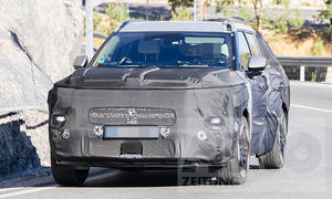 Der Hyundai Tucson (2026) fährt als Erlkönig auf einer Landstraße vor einer Felswand entlang, von vorne fotografiert.