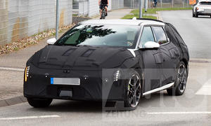 Der Kia EV4 GT (2026) fährt als Erlkönig in einen Kreisverkehr, von vorne links fotografiert.