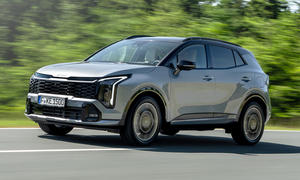 Der Kia Sportage (2025) fährt auf einer Landstraße, von vorne links fotografiert.