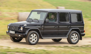 Die Mercedes G-Klasse (W463) fährt einen Feldweg entlang, von vorne links fotografiert.