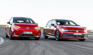 VW ID.3 GTX und VW Golf GTI fahren nebeneinander auf der Grand-Prix-Strecke des Nürburgring, von vorne fotografiert.