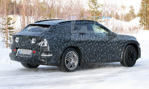 Das Mercedes-AMG SUV fährt als Erlkönig auf einer verschneiten Straße, von hinten rechts fotografiert.