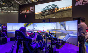 Bild zeigt Person auf einem Racing Rig und vor diversen Bildschirmen, die ein Rennspiel spielt.