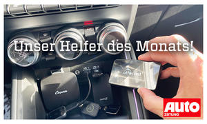 Das Bild zeigt den Wireless-Adapter für Apple CarPlay und Android Auto im Test. Mehrere Geräte liegen in der Mittelkonsole eines Autos, eine Hand hält ein weiteres Gerät ins Bild.