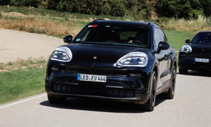 Der Prototyp eines Porsche Cayenne Electric (2026) fährt über eine Landstraße, fotografiert von schräg vorne.