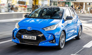 Der Toyota Yaris 1.5 VVT-i Hybrid 130 fahrend in der Innenstadt von schräg vorne fotografiert.