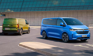 Der VW Transporter stehend von hinten fotografiert, der VW Caravelle von schräg vorne.