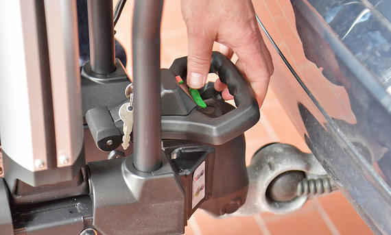 Fix4Bike-Anhängerkupplung - Zbigniew Mazar Die Außenaufnahme zeigt eine Heckbox auf dem Thule-Heckträger Easyfold3 (ohne Fix4Bike) am Heck eines Testwagens, die sich in der Kuve zur Seite neigt.