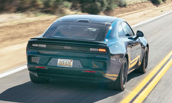 Dodge Charger Daytona (2025) - Olgun Kordal Der Dodge Charger Daytona (2025) fährt eine US-amerikanische Landstraße entlang, von hinten rechts fotografiert.