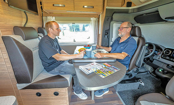 Die Sitzgruppe im Weinsberg CaraCompact Suite MB 640 MEG Edition Pepper (2025), zwei Personen sizten am Tisch.