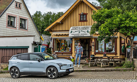 Der Volvo EX30 parkt vor einem urigen Shop am &quot;Elender Kreisverkehr&quot;, AUTO ZEITUNG-Redakteur Sven Kötter kommt aus dem Häuschen heraus.