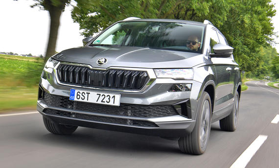 Der Skoda Karoq fährt auf einer Landstraße, von vorne links fotografiert.