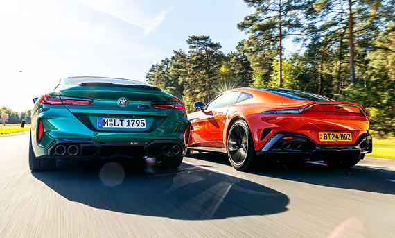 Der BMW M8 Competition &amp; der Aston Martin Vantage V8 fahren nebeneinander auf der Rennstrecke her. Blick von hinten.