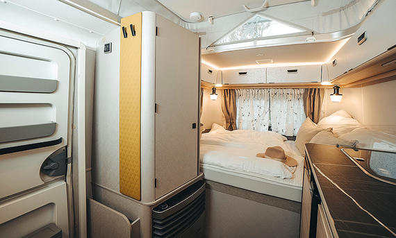 Eriba Touring 310 (2025) - Eriba Das Bild zeigt den Heckbereich des Wohnraums des Eriba Touring 310 (2025) mit Kleiderschrank links, Bett in der Mitte und Küchenzeile rechts.