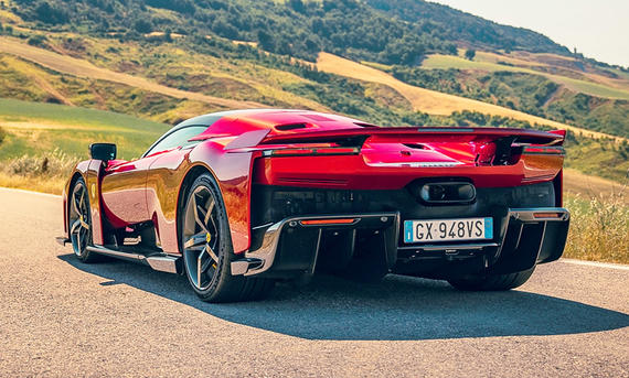 Der Ferrari F80 (2025) steht auf einer Landstraße zwischen Kornfeldern, fotografiert von hinten links.