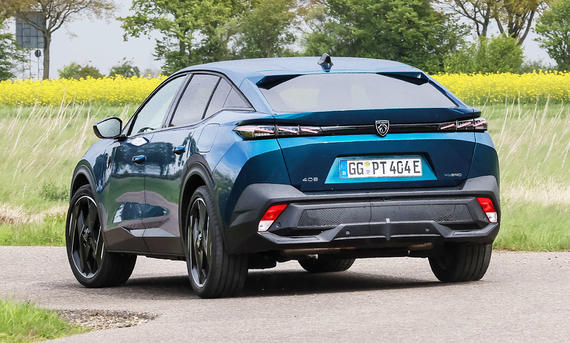 Der Peugeot 408 1.6 Hybrid 225 e fährt durch eine Kurve, von schräg hinten fotografiert.