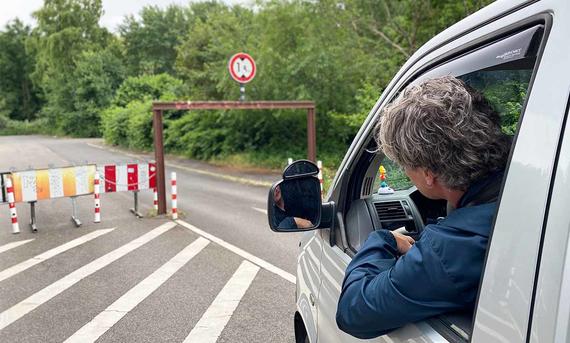 Garmin-Navi fürs Wohnmobil im Test - AUTO ZEITUNG Das Bild zeigt eine Tester am Steuer eines VW-Bus vor der Einfahrt zu einem höhenbeschränkten Parkplatz.