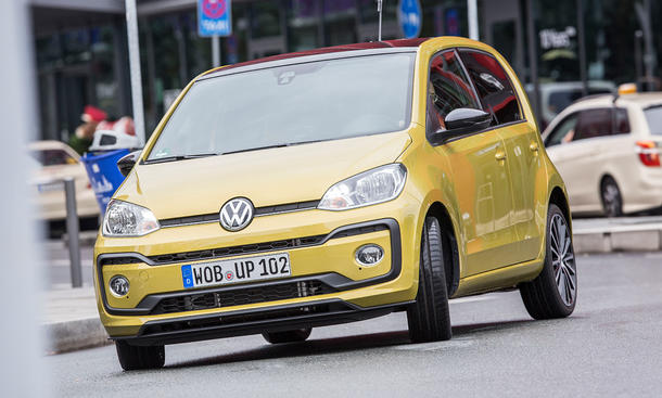 Der VW Up (2016) fährt in einer Stadt um eine Linkskurve, von vorne fotografiert.