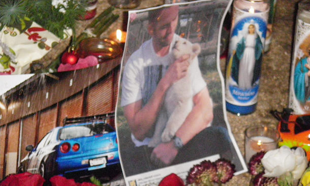 Paul Walkers Unfalltod: Foto zeigt von Fans errichtete Gedenkstätte am Unfallort, zu sehen sind ein Bild von Paul Walker und Kerzen.