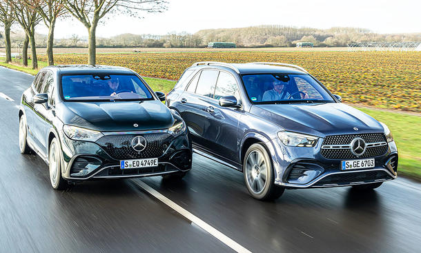 Mercedes EQE SUV und Mercedes GLE fahren nebeneinander auf einer Landstraße, im Hintergrund sind Felder zu sehen.