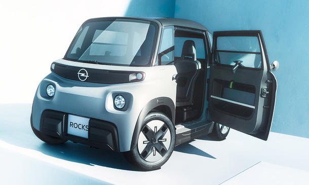 Der Opel Rocks (2025) steht mit geöffneter Fahrertür vor weißem Hintergrund, von vorne links fotografiert.