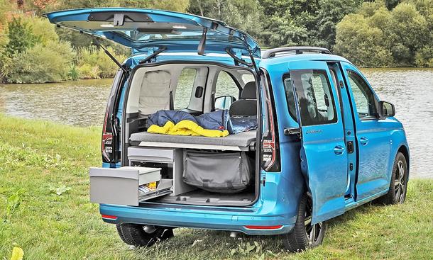 VW Caddy California (2020) auf einer Wiese am See geparkt, Heck geöffnet, Küchenzeile ausgezogen