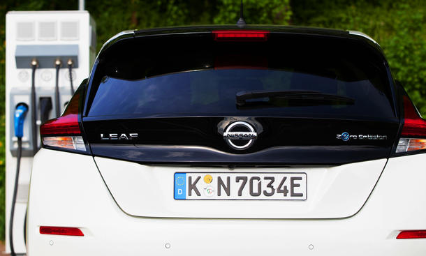 Das Heck des Nissan Leaf mit Blick auf das Kennzeichen, im Hintergrund steht eine Ladesäule.