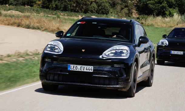 Der Prototyp eines Porsche Cayenne Electric (2026) fährt über eine Landstraße, fotografiert von schräg vorne.