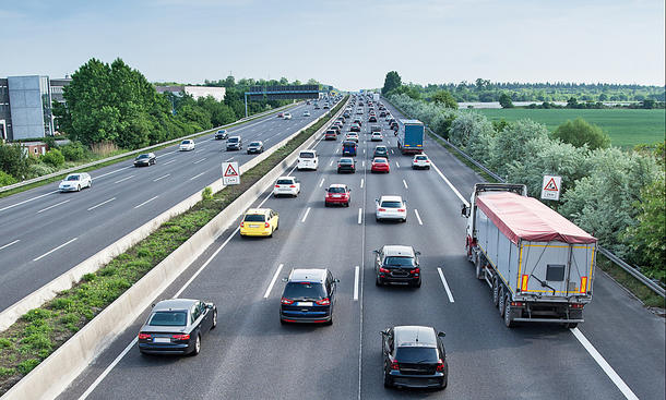 Eine stark befahrene vierspurige Autobahn aus erhöhter Perspektive in Fahrtrichtung fotografiert.
