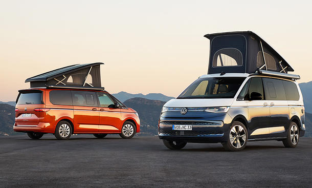 Das Bild zeigt zwei Versionen des VW California (2024). Beide stehen schräg zur Kamera mit geöffnetem Aufstelldach.