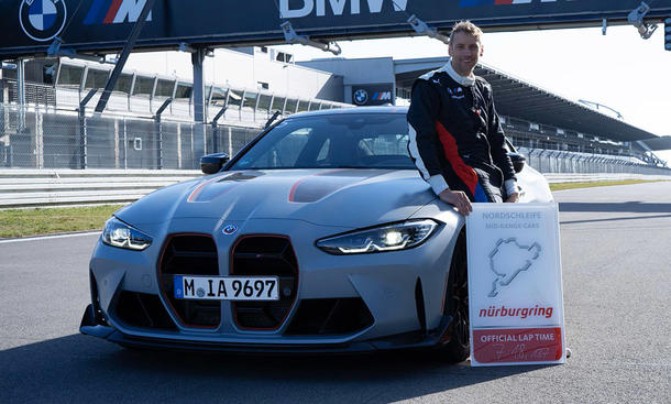 BMW M4 CSL fährt Nordschleifen-Rekord: Bild zeigt Fahrer Jörg Weidinger mit Rekordschild am Fahrzeug.