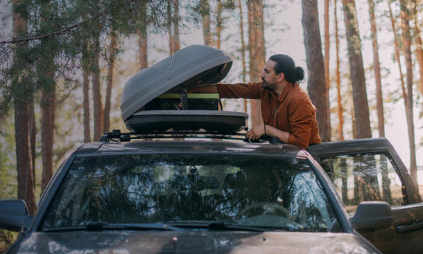 Auto mit Dachbox im Wald - eBay Mann öffnet Dachbox eines im Wald stehenden Autos.