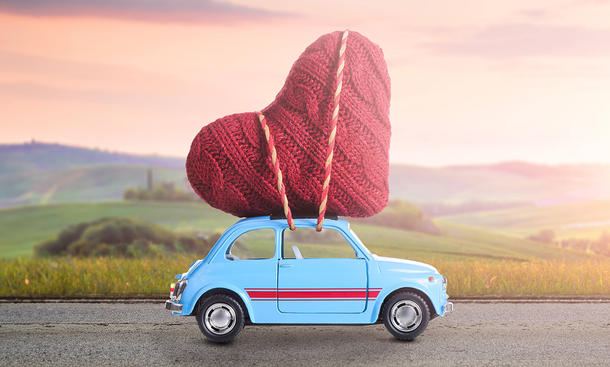 Modellauto (Fiat 500) mit Herz in Strickoptik auf dem Dach befestigt.