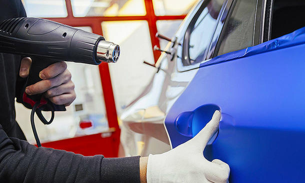 Heißluftfön - Imago Folie wird mithilfe eines Heißluftföns an ein Auto angebracht.