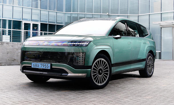 Hyundai Ioniq 9 (2025) - Hyundai Der Hyundai Ioniq 9 (2025) steht vor einer verglasten Fassade, von vorne links fotografiert.