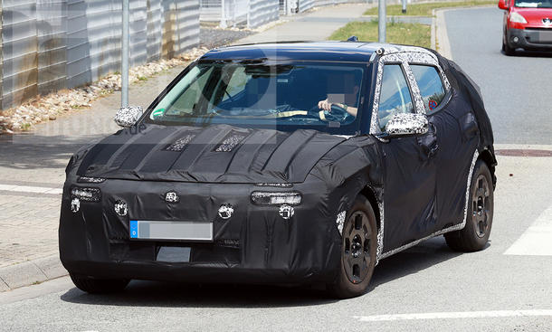 Der Hyundai Ioniq 2 (2026) fährt als Erlkönig in einen Kreisverkehr ein, von vorne fotografiert.