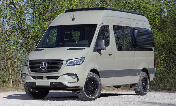 Der Mercedes Sprinter von Vansports steht auf einem Schotterparkplatz, von vorne links fotografiert.