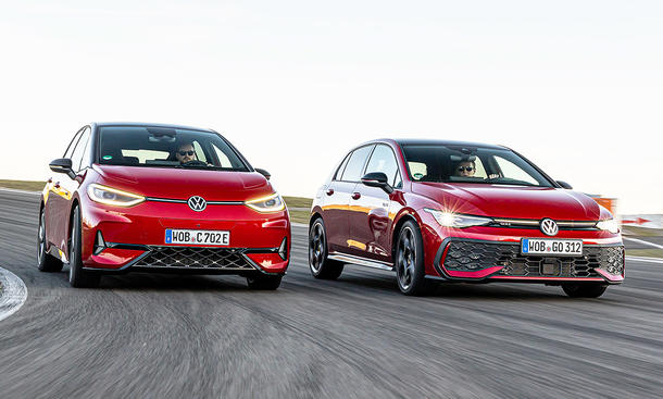 VW ID.3 GTX und VW Golf GTI fahren nebeneinander auf der Grand-Prix-Strecke des Nürburgring, von vorne fotografiert.
